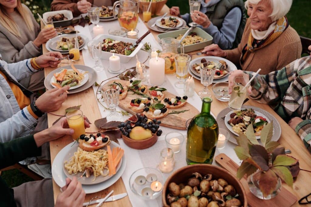 Grupo de invitados compartiendo banquete al aire libre con velas