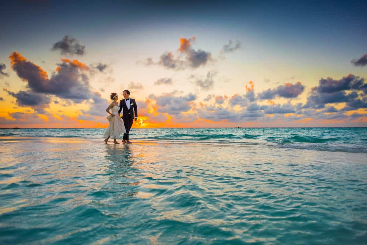 Pareja de novios paseando por la orilla del mar al atardecer