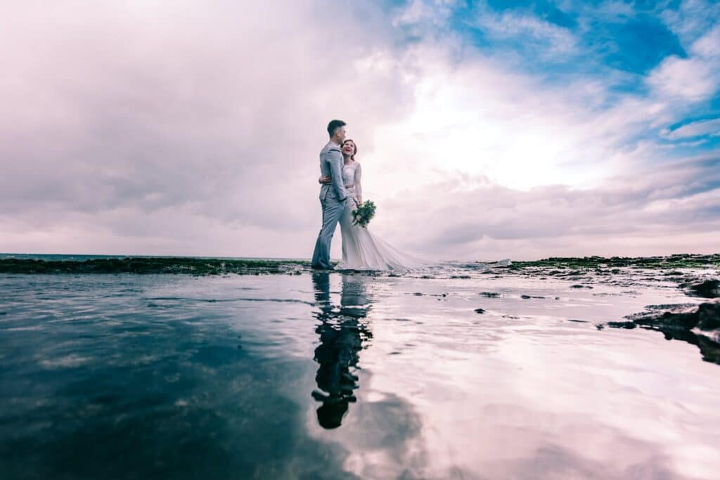 Pareja de novios abrazados junto al mar en su boda al aire libre